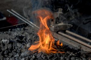 A burning forge with flames is pictured. Many serious burn injuries occur at work.
